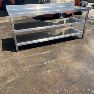 Mesa industrial acero inoxidable de segunda mano con peto trasero y dos estantes inferiores. Mesa industrial a