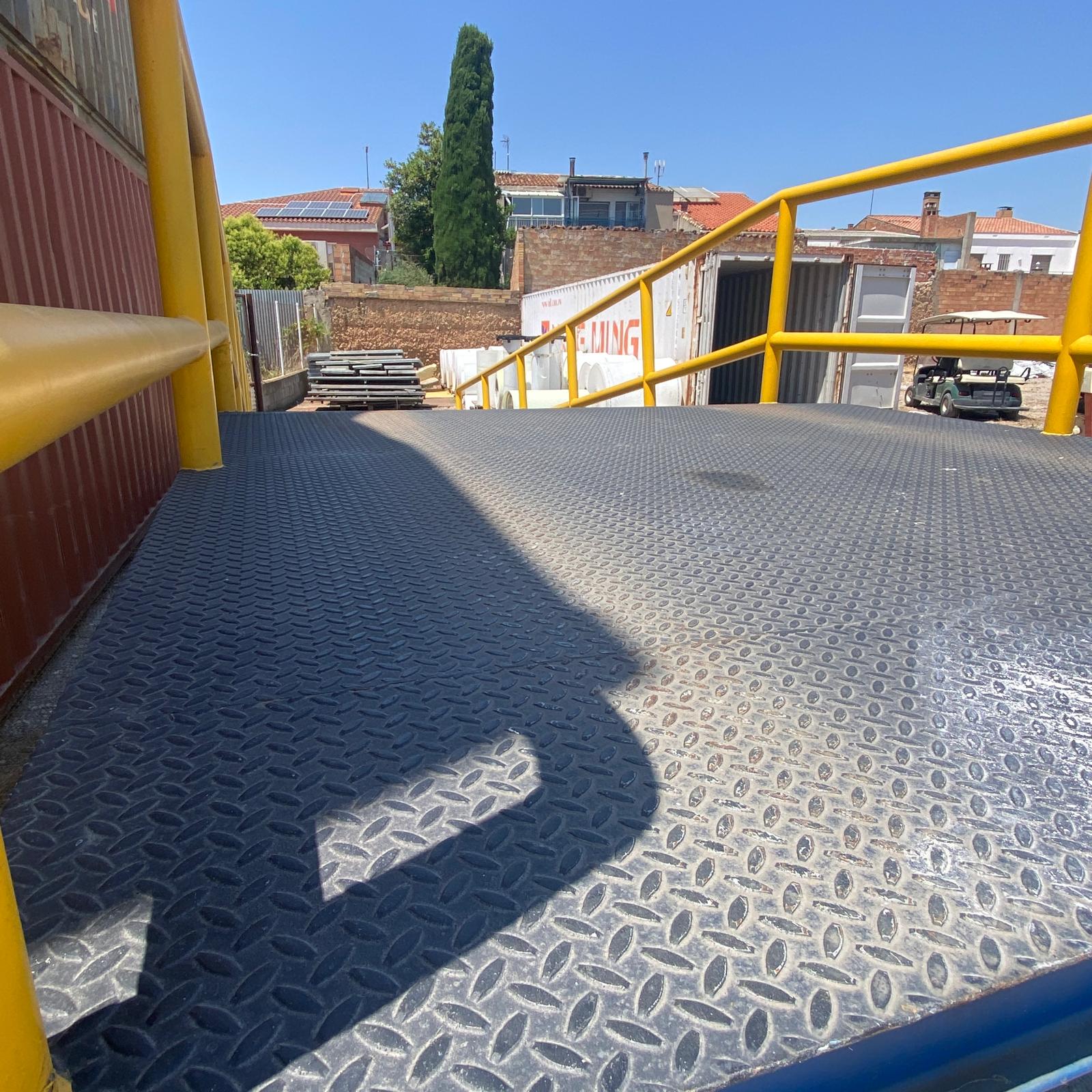 Detalle del suelo antideslizante de chapa lagrimada en rampa metálica industrial.